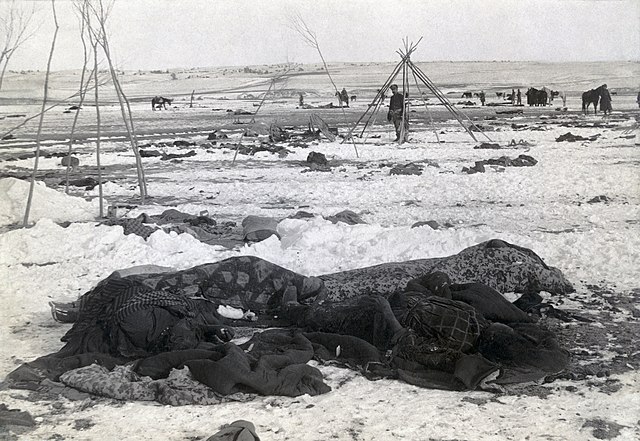 Big Foot's camp three weeks after Wounded Knee Massacre; with bodies of four Lakota Sioux wrapped in blankets in the foreground