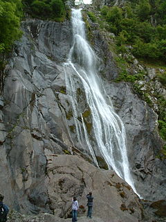 Ein großer Wasserfall, der 37 m über grauem Eruptivgestein stürzt und von Menschen beobachtet wird.