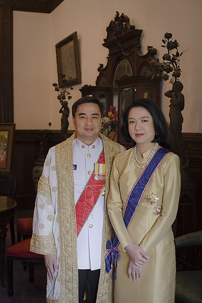 Abhisit Vejjajiva, wearing prime ministerial attire, including the golden brocaded Senamat gown (ครุยเสนามาตย์), and his wife, Dr Pimpen, wearing a Th
