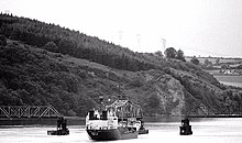 Ein Boot, das durch die Öffnung der Barrow Bridge fährt, wobei 3 Schlepperboote helfen