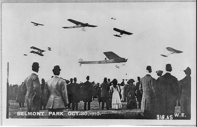 Photo composite of the 1910 event sponsored by the Aero Club of America "Crowd watching seven planes in air at the International Aviation Meet at Belm