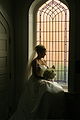 Bride sitting in front of a window of cathedral glass. Photo, Nils Fretwurst, 2005.