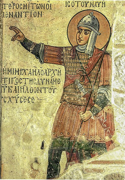 Byzantine fresco of Joshua from the Hosios Loukas monastery, 12th to 13th century. A good view of the construction of the lamellar klivanion. The image also shows the tubular nature of the upper arm defences of the raised arm, that is the defences are not made up of separate strips. Unusually, the Biblical figure (Joshua) is shown wearing headgear; the helmet and its attached neck and throat defences appear to be cloth-covered. It is possible that the figure depicts mail manikellia guards for the forearm (the forearms are not shown in the same green as the hem of the tunic and there is no appearance of folds as would be used to indicate cloth).