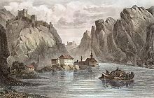 A river (Danube) flows in a steep-sided valley. To one side stands a medium-sized Abbey, and a castle, in ruins, overlooks the valley. A boat floats in the middle of the river.
