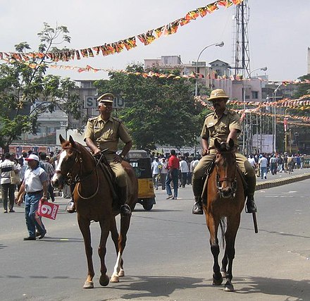Chennai City Mounted Police officers patrolling in their khaki colored uniform during a cricket match.