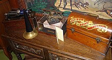 A brick of the Syria Mosque building (center), exhibited in the Bayernhof Museum alongside an Edison cylinder phonograph (left) and Edison home phonograph (right) Edison cylinder phonograph, Syria Mosque brick, and Edison Home Phonograph - Bayernhof Museum - DSC06361.JPG