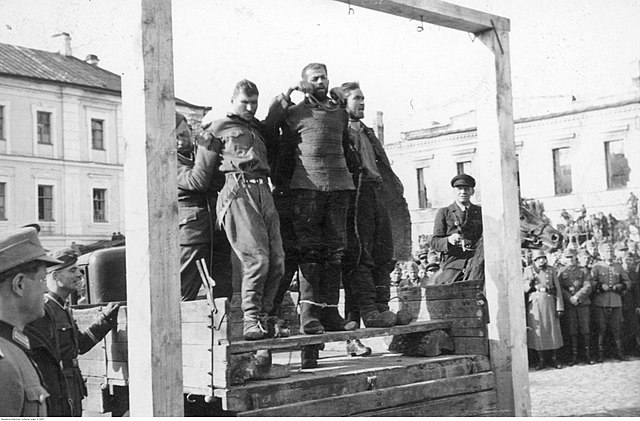 Three men about to be hanged in front of a large crowd of Wehrmacht soldiers