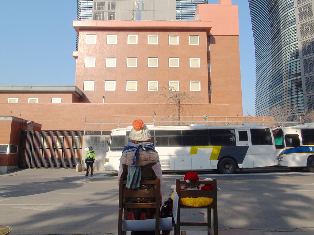 1024px-Japanese_Embassy_in_Seoul_and_watched_from_behind_a_bronze_statue_of_comfort_women.JPG