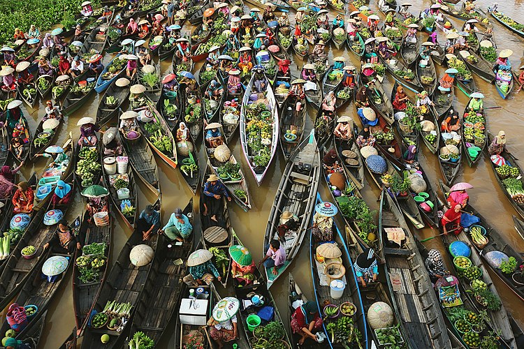 Торговля с лодок на плавучем рынке банджаров в Индонезии