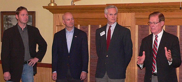 Four serious-looking men in dark jackets