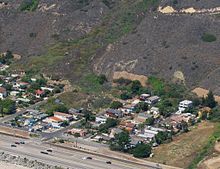 View of the main 2005 landslide, from the air, just offshore. Prior to 2005 the houses formed a straight line along the base of the hill.