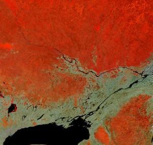 In this false-colour satellite image, the Ottawa River flows southeast, joining the St. Lawrence River which flows northeast. Heavily forested areas a