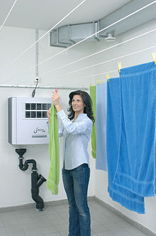 Laundry hung on a clothes line in a drying room (dehumidifier in the background and duct for ventilation in the ceiling) Raumluft waeschetrockner.jpg