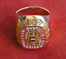 The ring of honour until 2013, with a seal containing the stylized coat of arms of Austria and the words sub auspiciis Praesidentis Ringsubauspiciis.jpg