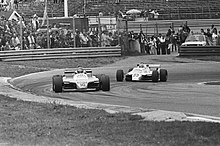 Photo en noir et blanc de deux monoplaces de Formule 1 négociant un virage.