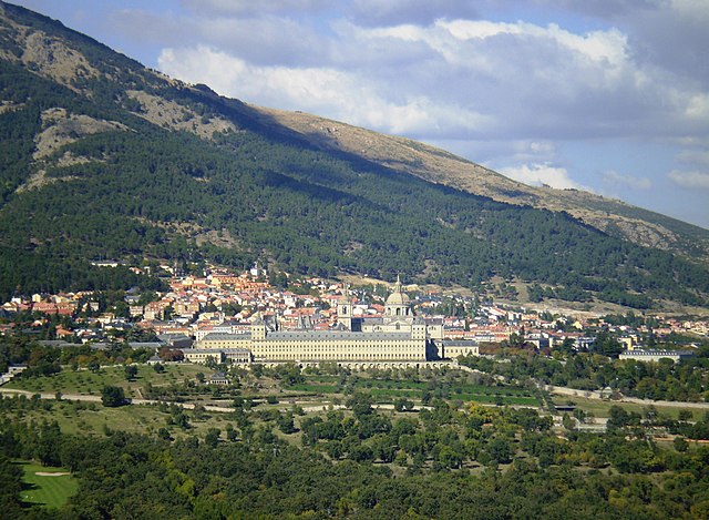 View of San Lorenzo de El Escorial, on the slopes of Mount Abantos, from the Silla de Felipe II [es] (Seat of Philip II). In the foreground, the Monas