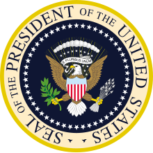 En un círculo, se representa un águila en el centro con varios símbolos, incluido un escudo de armas con los colores de los Estados Unidos, y alrededor de este diseño está escrito en inglés: sello del presidente de los Estados Unidos de América.