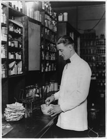 Pharmacist compounding a medication using a mortar and pestle (c. 1923) The drug clerk LCCN2002712838.jpg