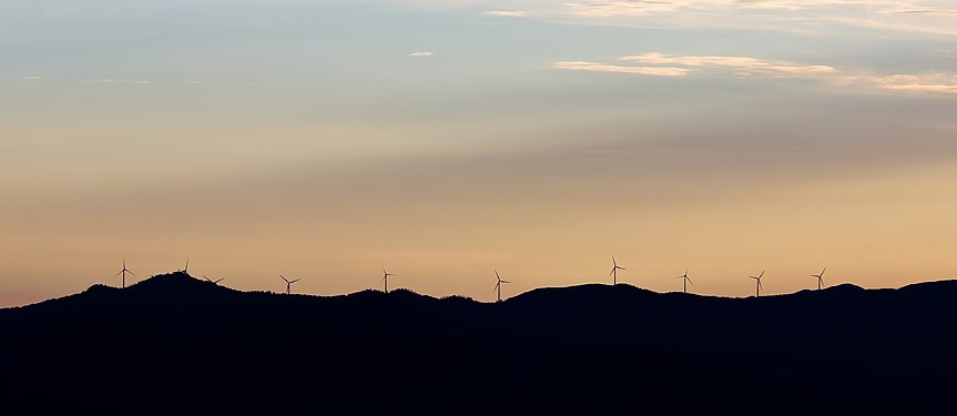 Twilight in Tuscany, wind turbines on a hill range.