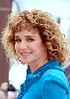 Valeria Golino at the 2016 Cannes Film Festival with curly hair, looking to the front, wearing a blue shirt and smiling