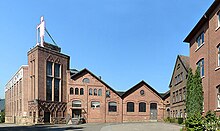Sitz der Firma Idealspaten in Herdecke, ein industrieller Backsteinbau mit dem symbolisierten „Spatenmann“ auf dem Dach