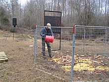 A corral-type trap being baited. Food is left to accustom pigs to using the trap as a daily food source; eventually, the gate can be triggered remotely when most or all the members of a sounder are inside the trap 20140402-APHIS-UNK-0020 (13592902154).jpg