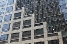 Detail der umgebauten Fassade des Kress-Gebäudes an der Fifth Avenue.  Die untere Marmorwand erhebt sich treppenartig vor der oberen Wand, die aus Glas besteht.