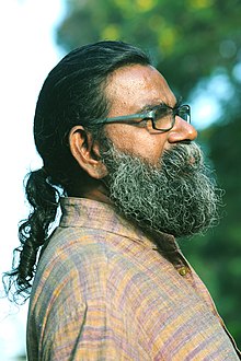 Rajasekharan Parameswaran with ponytail and long beard, wearing a patterned shirt, standing in profile