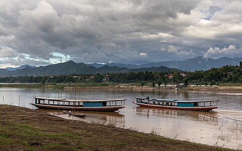 Boats on the Mekong with dark clouds and blue sky in the late afternoon in Luang Prabang Laos