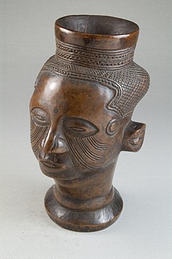 Wooden cup in the shape of a human head with stylized features from the Kuba culture. Cheeks have curved multilinear facial markings. Brooklyn Museum 22.126 Single Head Goblet Mbwoongntey.jpg