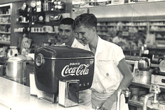 "Soda jerks" dispensing Coca-Cola at Fleeman's Pharmacy, Atlanta, Georgia, circa 1948. This photo documents the first-ever installation of this model of "Boat Motor"-styled Coca-Cola dispenser. FLEEMANSpharmacyCOKErwLIPACKowner.jpg