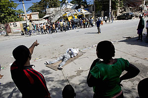 Haitian look at a body pulled out from the rubbles of a school (12 january 2010).jpg