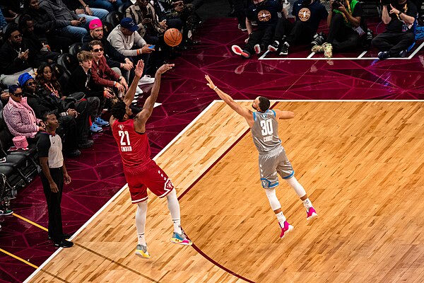 Joel Embiid shoots a three-point shot over Stephen Curry during the 2022 NBA All-Star Game.
