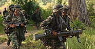 The Malaysian Army operator (left) holding the M-16A1 carbine.