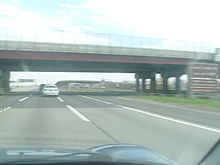 Eine große Brücke über einer 12-spurigen Autobahn von einem Auto aus gesehen