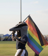 Peter waving a traditional pride flag at UC Irvine’s Crawford Field during a soccer game