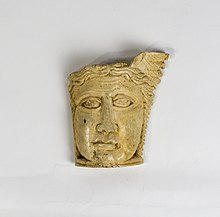 A face carved on a piece of curved bone. The face is framed by hair and part of a winged head-dress remains. Coptic Roman Bone Carving.jpg