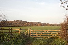 wooden gate with field and low hill beyond