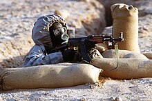A Syrian soldier aims a Type 56 assault rifle wearing a Soviet-made, model ShMS nuclear-biological-chemical warfare mask. Syrian soldier aims an AK-47.JPEG