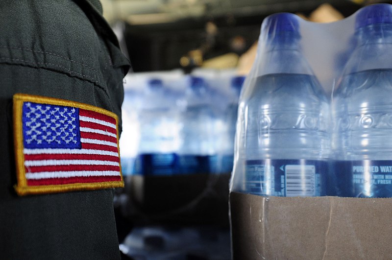 File:US Navy 100116-N-6006S-059 An air crewman from Helicopter Sea Combat Squadron (HSC) 9 stands next to cases of drinking water that will be distributed to earthquake survivors.jpg