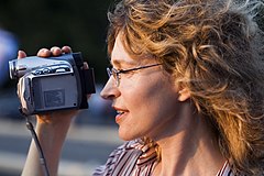 A young smiling woman recording, digital movie camera in hand, Rome, Italy