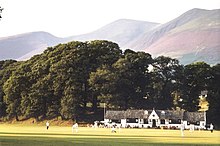 Cricket ground with wooded hills at the rear