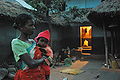Adivasi mother child before lighted house.jpg