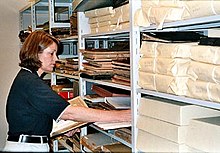 An archivist surveying an unprocessed collection of materials. Surveying is commonly done to determine priorities for preservation and/or conservation of materials before an archivist begins arrangement and description. Archivist Survey.jpg