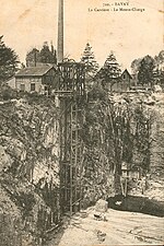 Carte postale ancienne montrant la carrière de grès avec son monte-charge ; une cheminée révèle la présence d'une machine à vapeur pour actionner les engins ; les couches de roches sont presque à la verticale