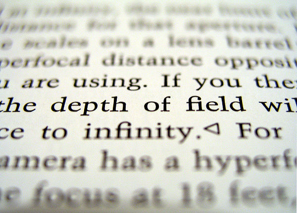 A macro photograph showing the defocused effect of a shallow depth of field on a tilted page of text