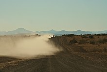 Bulldust billowing up behind a vehicle driving along a dirt track Dust in the track.jpg