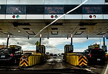 A view of the San Francisco-Oakland Bay Bridge toll plaza in 2008. The center and right toll booths are labeled "Fastrak Only", while the left toll booth accepts cash and Fastrak. Cash payment was phased out during the COVID-19 pandemic and replaced with license plate tolling, and now all booths read "Fastrak or Invoice" other than the HOV lane. Fastrak only (7730815530) (2).jpg