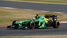 Fotografia di una monoposto di Formula 1 verde e gialla, vista di tre quarti.
