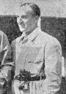 Photo en portrait d'Hermann Lang, debout en tenue de pilote.